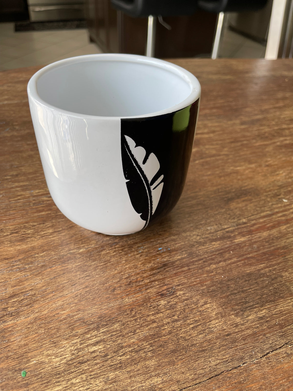 White glossy ceramic cup pot with a black side panel and white fern leaf cutout